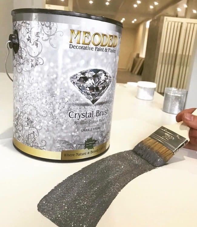 A gallon of Meoded Crystal Brush beside a brushed-out stroke of the glitter paint