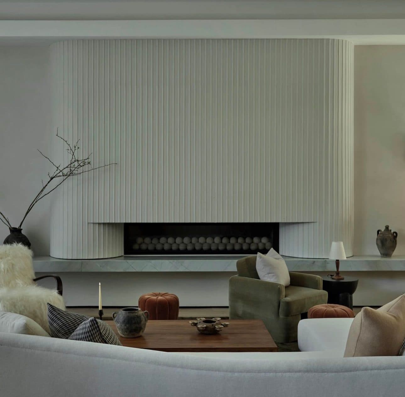 A curved fireplace surround fluted in Meoded Marmorino Intonaco, in a softly lit living room