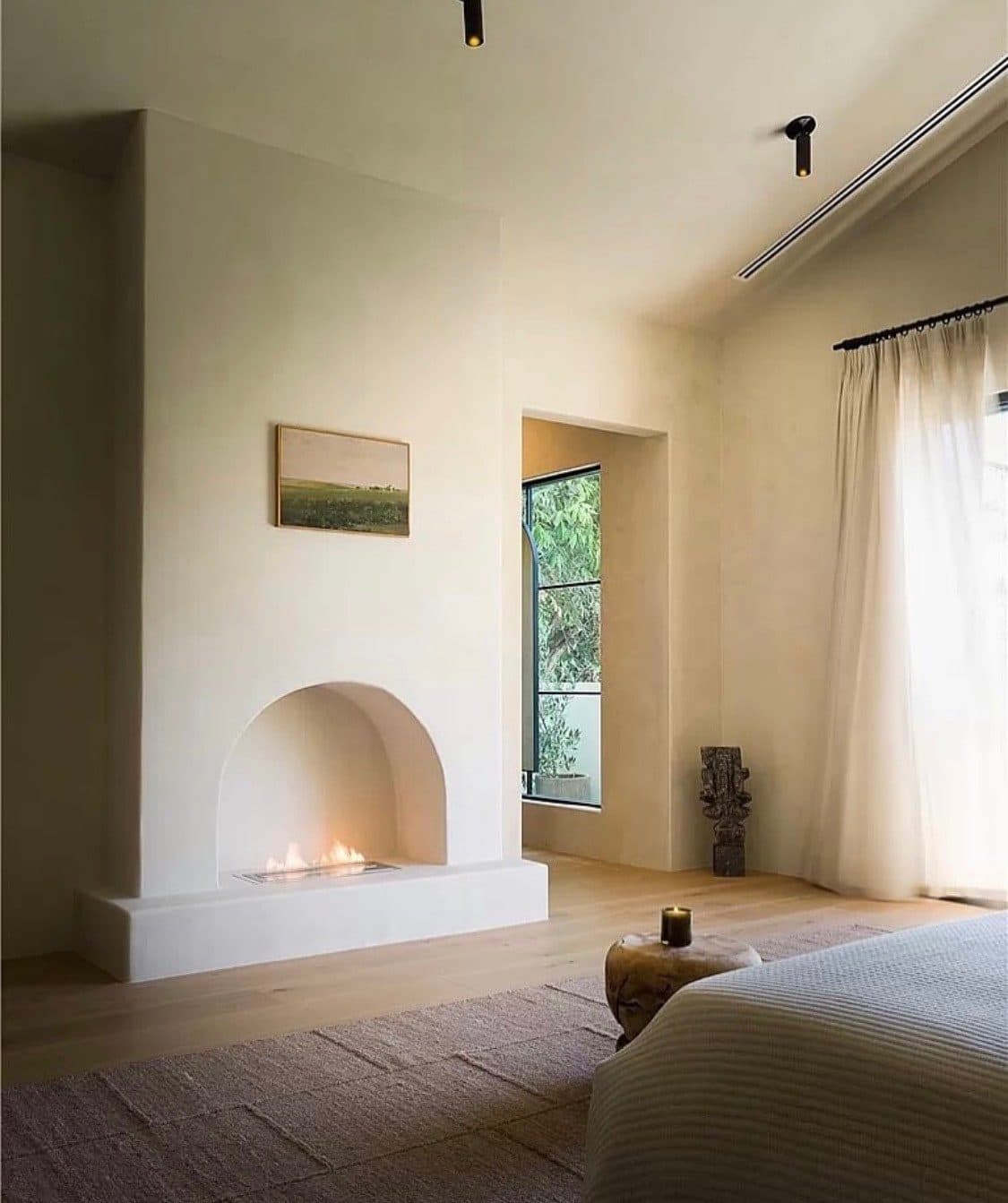 A bedroom with an arched fireplace, the walls and chimney finished in soft, matte Meoded Moroccan Clay