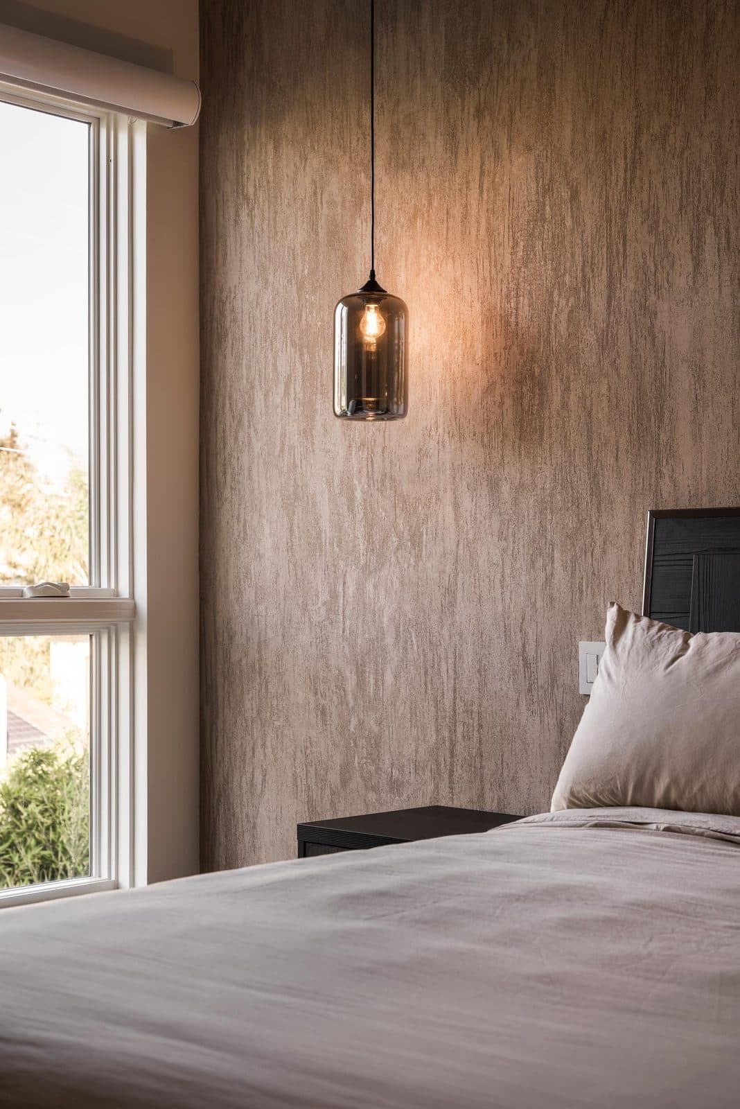 A bedroom wall in Meoded Marmorino Palladino, its trowel marks catching window light